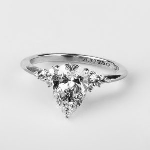 A timeless symbol of elegance, the Celeste ring features a dazzling pear-cut diamond flanked by a trio of accent stones on each side, set in 18K white gold. A perfect blend of grace, brilliance, and modern sophistication.