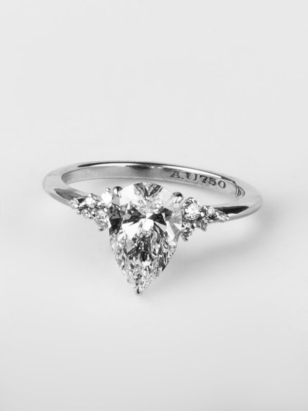 A timeless symbol of elegance, the Celeste ring features a dazzling pear-cut diamond flanked by a trio of accent stones on each side, set in 18K white gold. A perfect blend of grace, brilliance, and modern sophistication.
